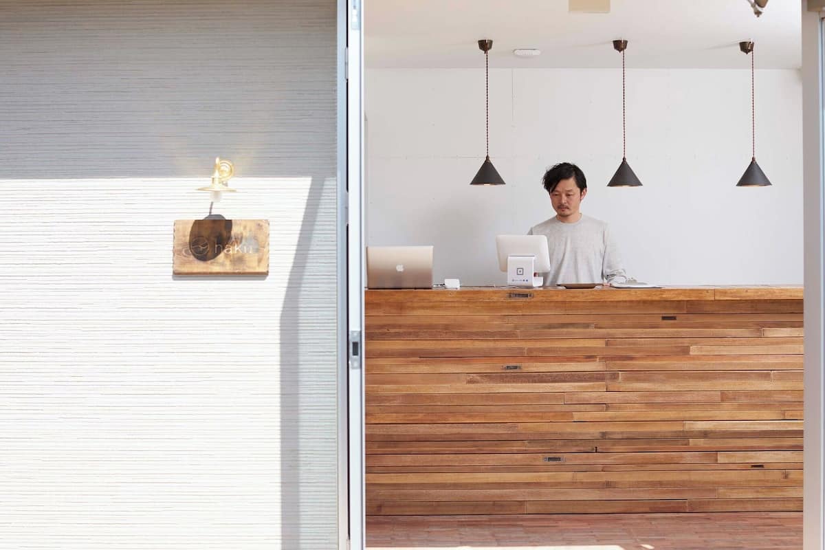 Un mostrador de recepción con paneles de madera, una computadora portátil y una máquina de café.