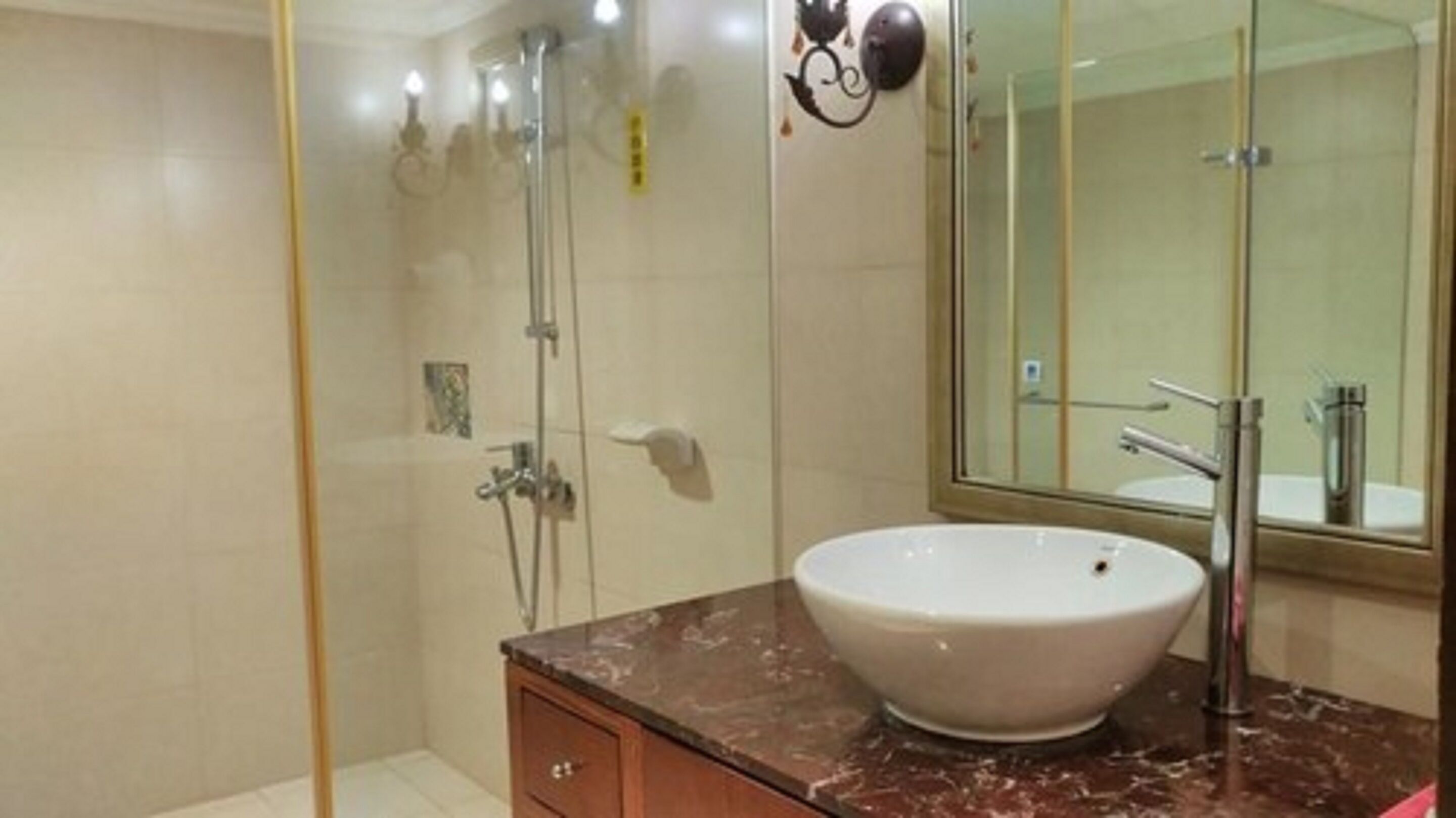 A bathroom with a large mirror, a white sink, and a shower area.