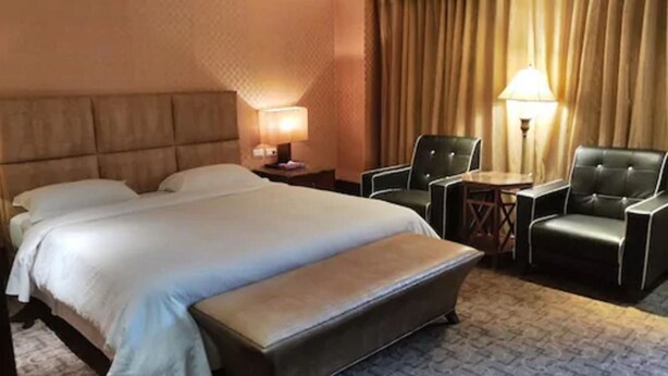 A hotel room with a large bed, two chairs, a small table, and a lamp. - Kai Wei Boutique Hotel (Taipei)
