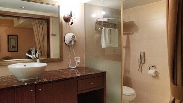 A bathroom with a marble sink, a mirror, a towel rack, a glass shower enclosure, and a toilet.