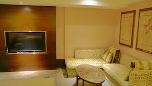 A hotel room with a sofa, a small table, a TV mounted on a wooden panel, and patterned carpet. - Kai Wei Boutique Hotel (Taipei)