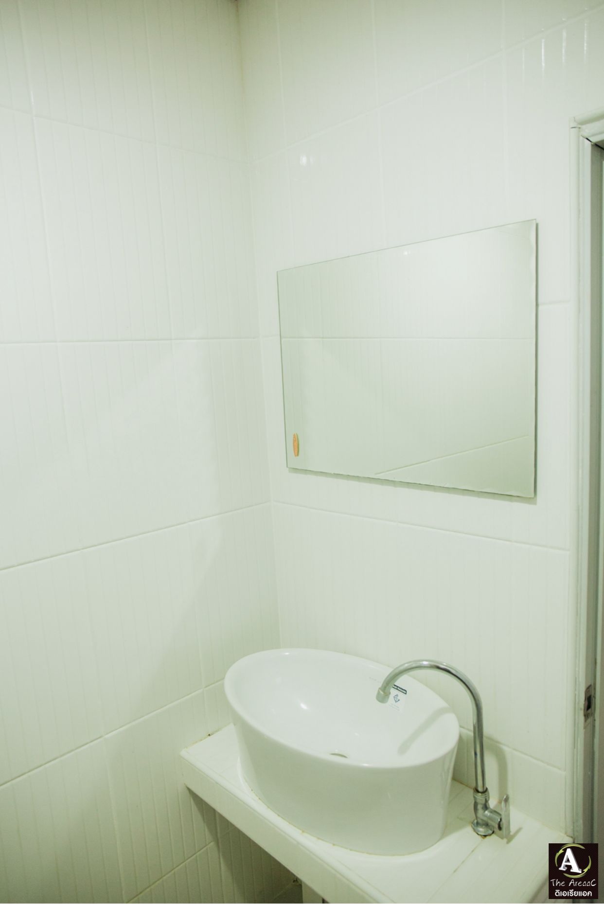 A bathroom with a white sink, a mirror, and white tiled walls.