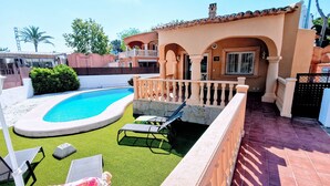 A swimming pool with a curved edge, surrounded by artificial grass. There are lounge chairs and a covered seating area. - 0302 Villa Monte Verde Pera (Javea / Xàbia)