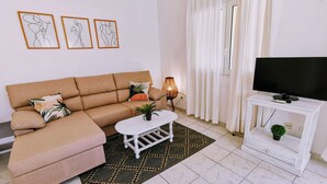 A living room with a sofa, a coffee table, a TV on a stand, and a patterned rug. - 0302 Villa Monte Verde Pera (Javea / Xàbia)