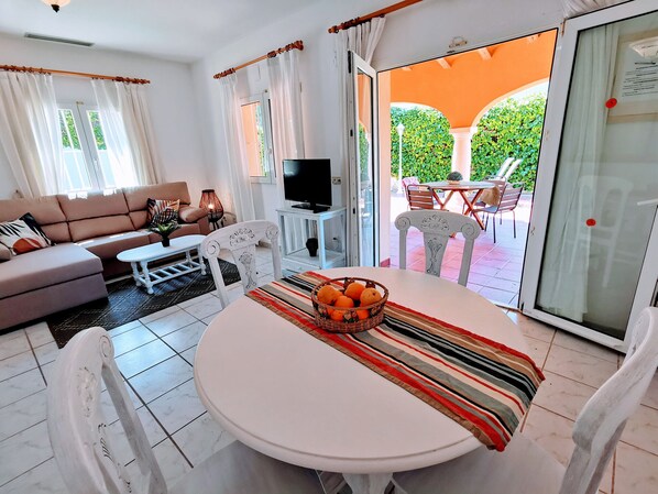 A modern living room with a sofa, TV, and dining area with a table and chairs.