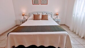 A neatly made bed with a white and brown bedspread, two bedside lamps, and two framed artworks on the wall. - 0314 Villa Monte Verde Cereza (Javea / Xàbia)