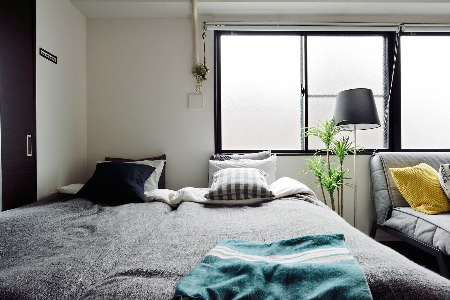 A bedroom with a bed, a bedside table, a lamp, and a window.