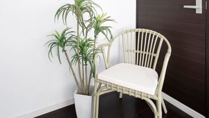 A framed handwritten note on a wall, a potted plant, a white chair, and a dark wooden door. - nid NIPPONBASHI at Ebisu (Osaka)