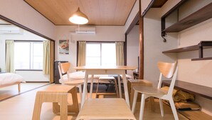 Una camera moderna con soffitto in legno, un tavolo da pranzo con sedie, un letto e una finestra con tende.