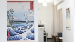 Una stanza con un'ampia opera d'arte raffigurante una scena con le onde, un termosifone bianco e un lampadario.