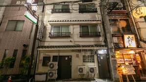 Un edificio a più piani con condizionatori d'aria, l'ingresso di un negozio chiuso e un cartello.