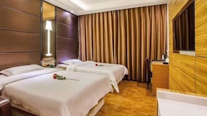 Una habitación de hotel con dos camas, cabecero de madera, un espejo grande y un armario de madera.