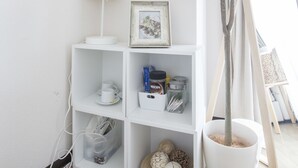 Un estante blanco con un cuadro enmarcado, una máquina de Nespresso y objetos decorativos.