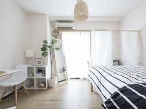 Ein modernes Schlafzimmer mit Bett, Nachttisch, Sessel, Schreibtisch und einer Topfpflanze.