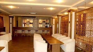 Uma área de bar com um balcão comprido, vários bancos e uma parede estampada.