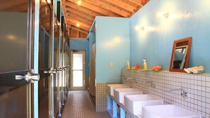 Un baño con tres lavamanos, un espejo y un revestimiento de azulejos.