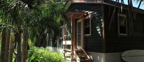Une maison en bois avec un porche et une planche de surf appuyée contre le mur.