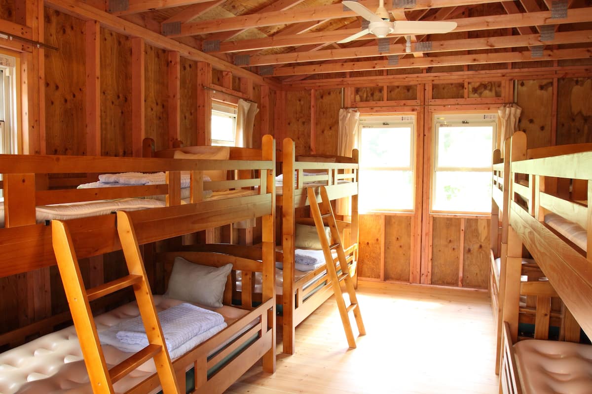 Une cabine avec des lits superposés, des murs en bois et un ventilateur de plafond.