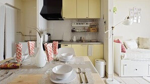 A modern kitchen with yellow cabinets, a black range hood, and a dining area with a table set for two. - nid Shimanouchi House (Osaka)