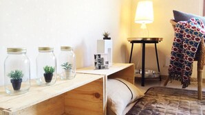 A cozy room with a wooden desk, a lamp, a blanket, and jars with plants. - nid Shimanouchi House (Osaka)