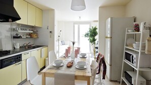 A compact kitchen with a dining table, chairs, a refrigerator, and a stove. - nid Shimanouchi House (Osaka)
