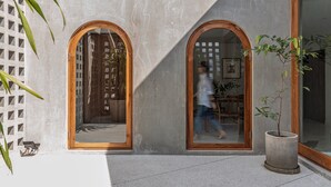 A building with two arched windows, a concrete exterior, and a potted plant. - The Earth Hotel (Chiang Mai)