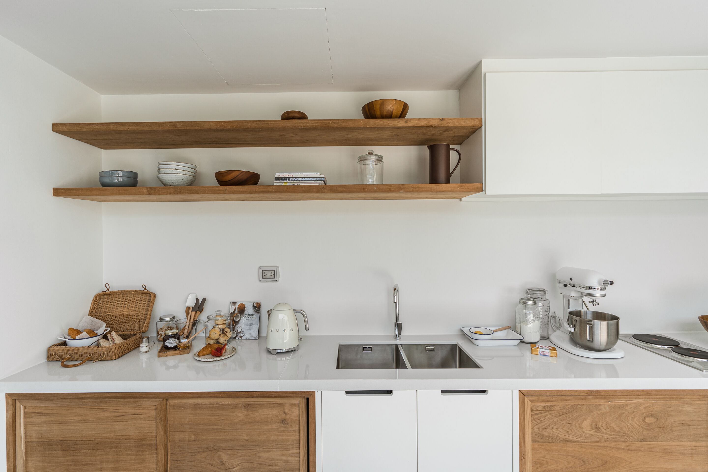 A modern kitchen with wooden shelves, a white countertop, and stainless steel appliances.