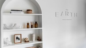 A white interior with a bookshelf containing books, a bowl, and decorative items. - The Earth Hotel (Chiang Mai)