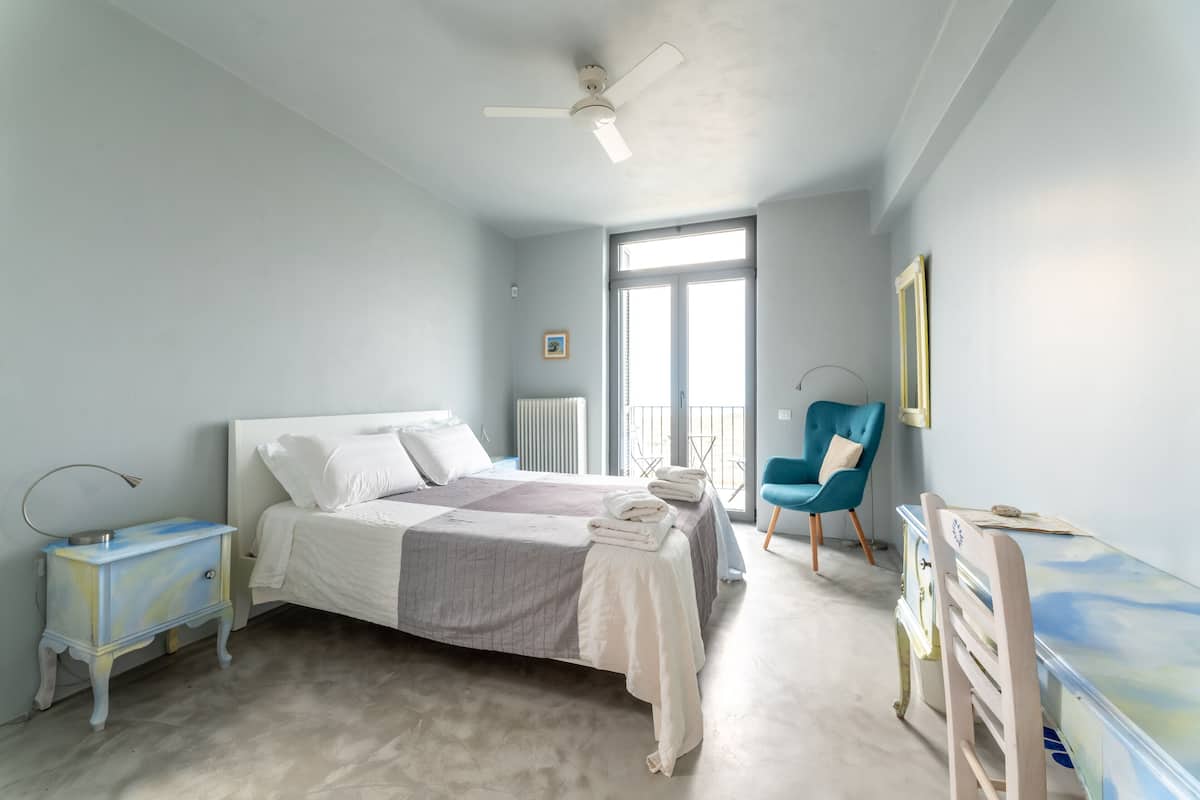 A bedroom with a bed, bedside tables, a chair, a dresser, and a window.