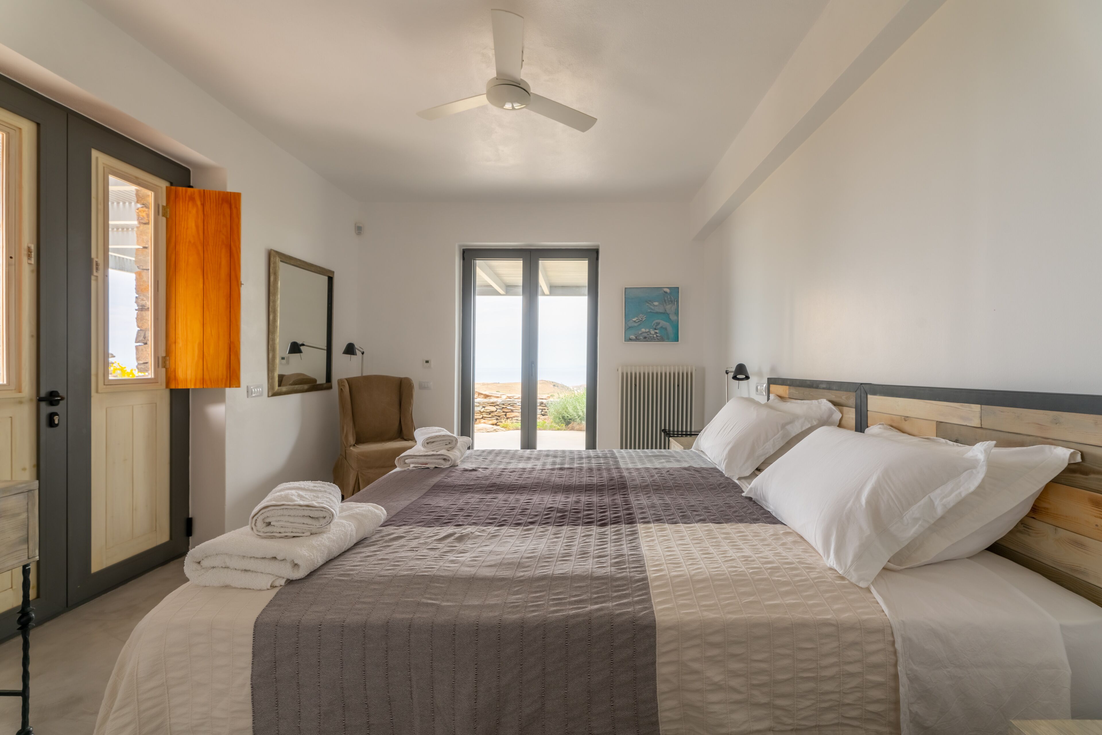 A bedroom with a bed, a chair, a window, and a door.