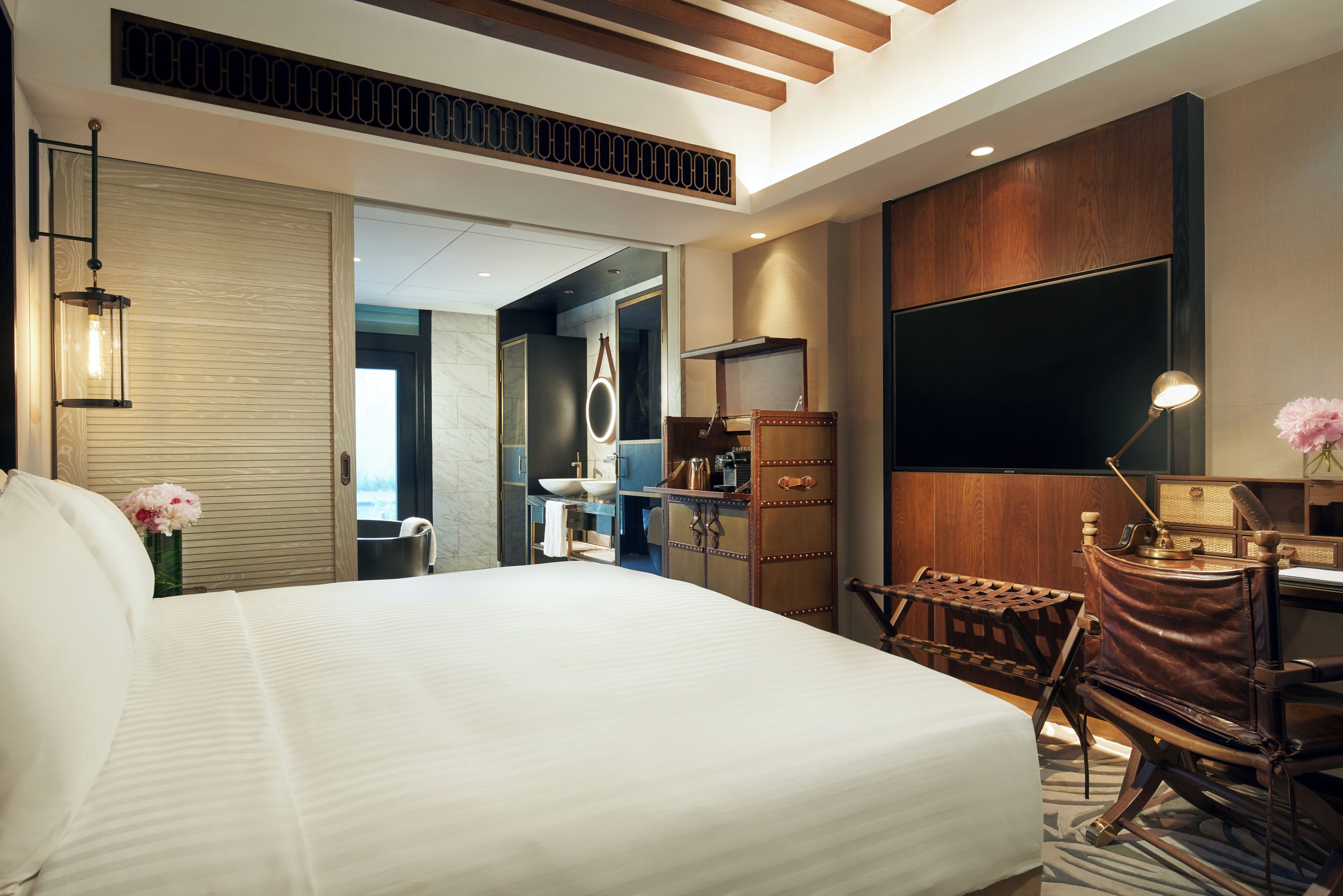 Een moderne hotelkamer met een groot bed, een bureau, een stoel, een flatscreen televisie en een houten kast.