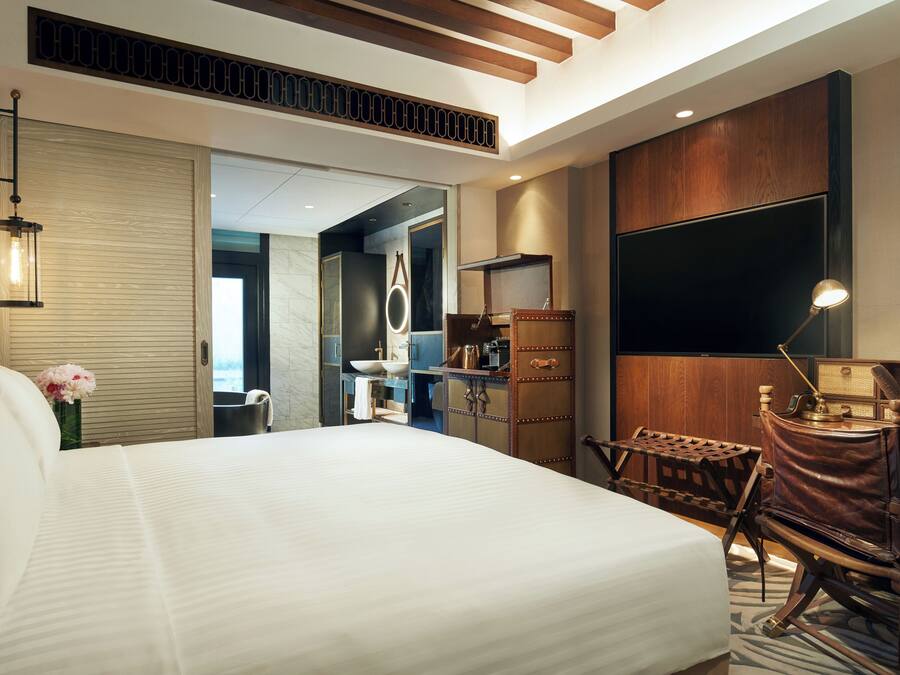 Een moderne hotelkamer met een groot bed, een bureau, een stoel, een flatscreen televisie en een houten kast.