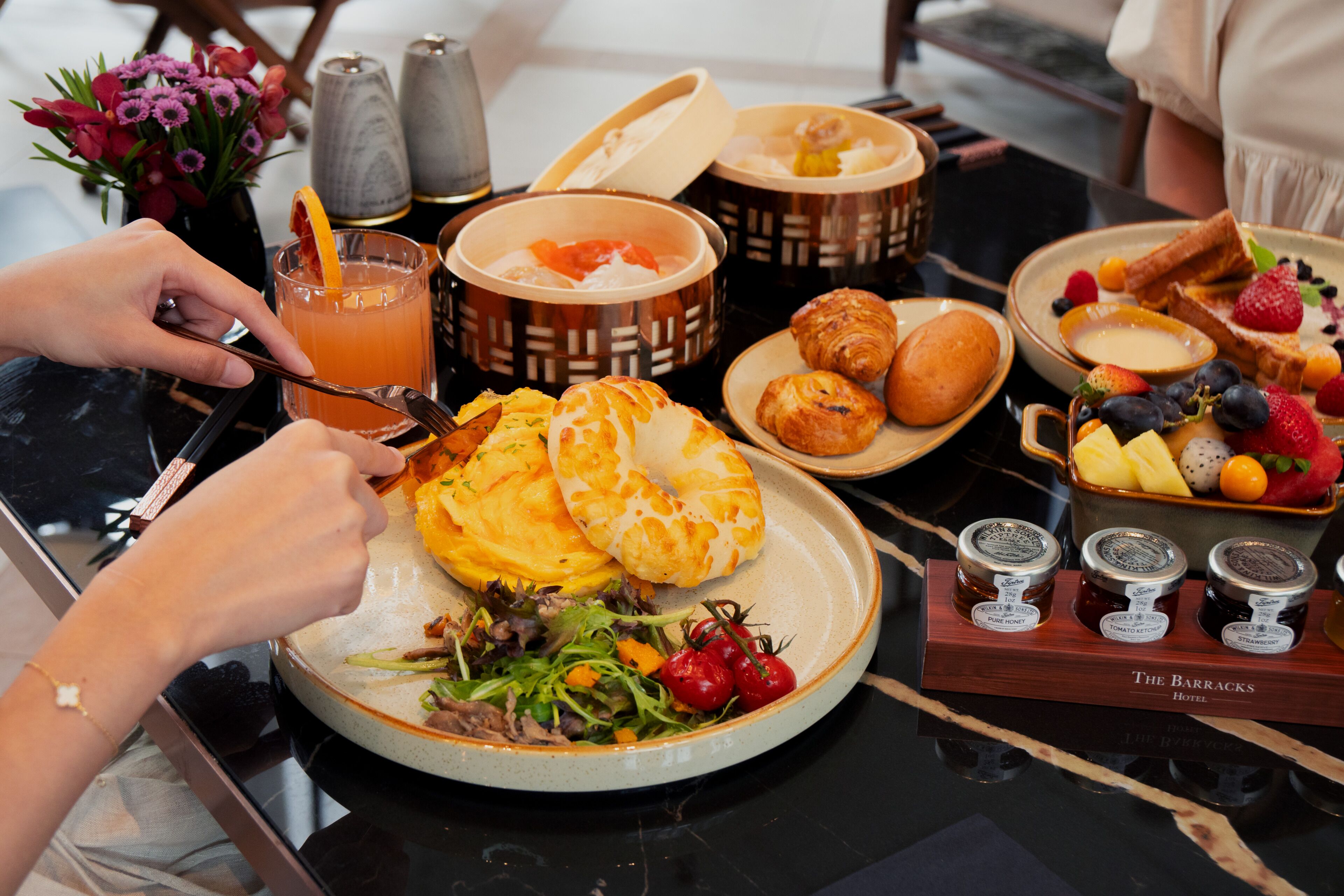 A breakfast setting with a variety of food items including pastries, fruits, and a salad.