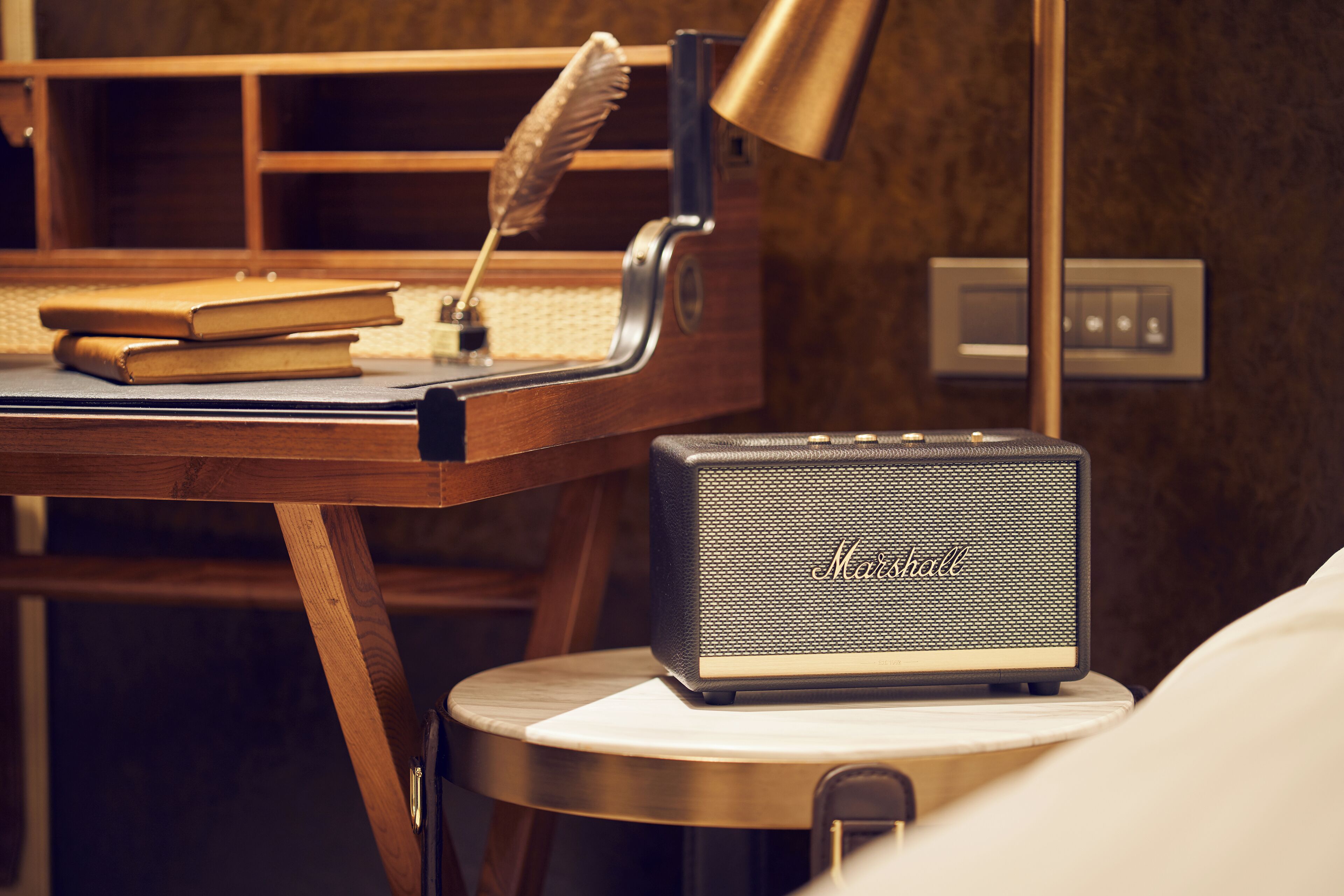 A desk with a vintage Marantz speaker, a feather quill, and books, suggesting a study or work area.
