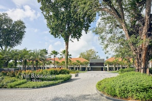 The Barracks Hotel with a paved walkway, lush greenery, and a modern building in the background. - The Barracks Hotel Sentosa by Far East Hospitality (Singapore)