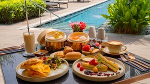 Un bufé de desayuno con diversos platos, una taza de café y un entorno junto a la piscina.