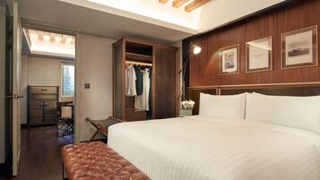Une chambre d’hôtel avec un grand lit, un banc, une armoire et un bureau.