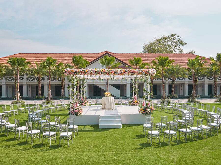 An outdoor wedding setup with a stage, chairs, and floral decorations.
