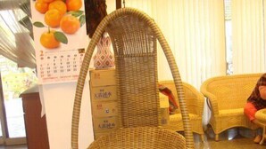 En fletstol med metalstel i et rum med flisegulv og en gul sofa i baggrunden.