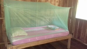 A wooden bed with a mosquito net and a pink mattress. - Jungle Reps (Iquitos)