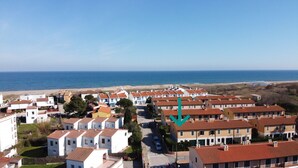 A coastal residential area with terraced houses, a clear view of the sea, and a road leading to the beach.