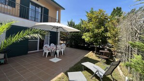 A patio with a table and chairs, a lounge chair, and a large umbrella.