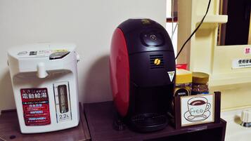 Una tetera eléctrica y una cafetera sobre una mesa de madera con un letrero que indica café gratis.