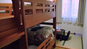 Uma cama beliche com colcha florida, uma mesa pequena com cadeira e um futon.