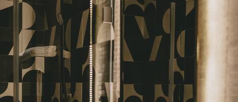 A bathroom with a geometric patterned wall, a white sink, and a mirror.