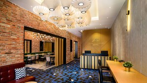 A modern interior with a brick wall, a reception desk, seating areas, and patterned flooring. - Macalister Hotel Managed By The Ascott Limited (George Town)