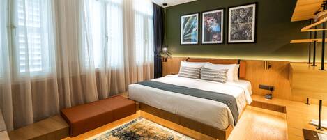 Une chambre d’hôtel moderne dotée d’un grand lit, d’un coin salon et d’œuvres d’art accrochées aux murs.