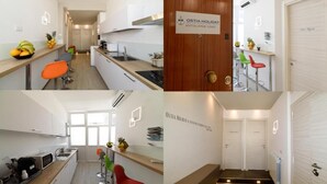 Una cocina moderna con armarios blancos, encimera de madera y un frutero. Hay dos taburetes de bar y un lavamanos. La imagen también muestra una puerta con un letrero que dice 'OSTIA HOLIDAY'.