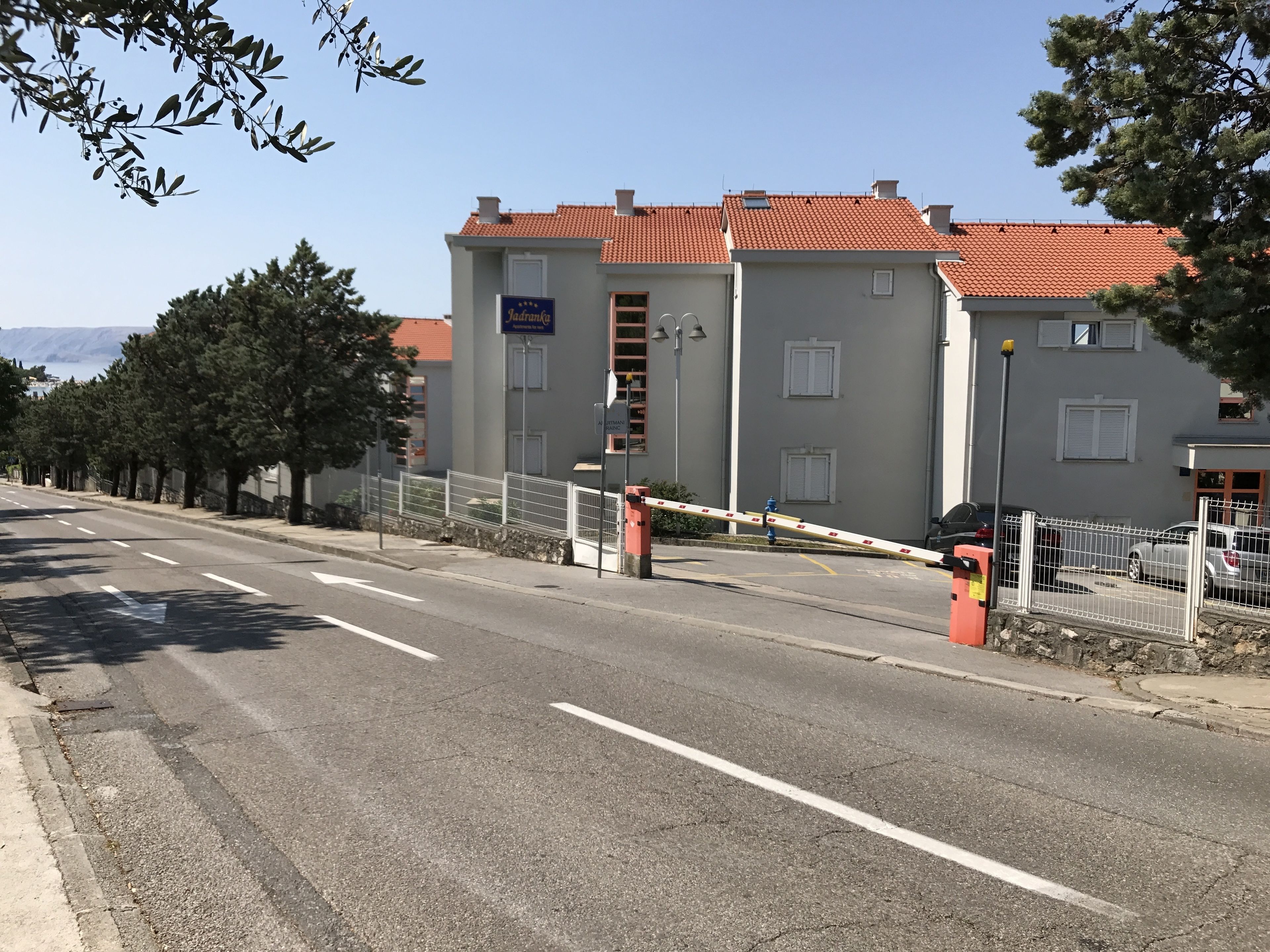 Una calle con una entrada porticada a un edificio, cielo despejado y árboles a lo largo de la acera.