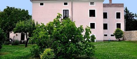 Un edificio de dos pisos con fachada rosa, varias ventanas y un pequeño balcón.